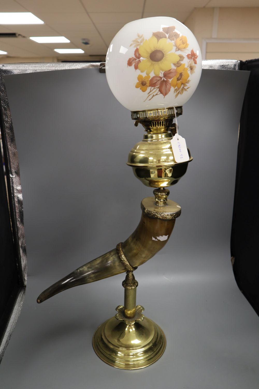 A brass oil lamp, with horn stem, 23in.